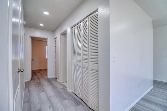 hall featuring recessed lighting, light wood-type flooring, and baseboards