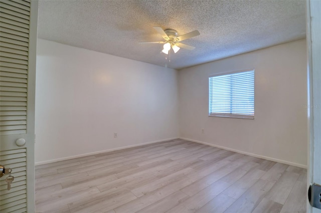 spare room with a textured ceiling, baseboards, light wood-type flooring, and ceiling fan