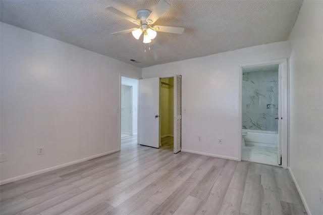 unfurnished bedroom with a closet, baseboards, a textured ceiling, and light wood-style flooring