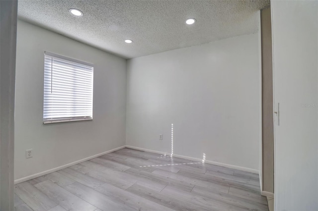 spare room featuring recessed lighting, light wood-style floors, baseboards, and a textured ceiling