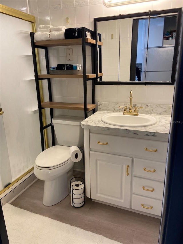 full bath with vanity, wood finished floors, a stall shower, decorative backsplash, and toilet