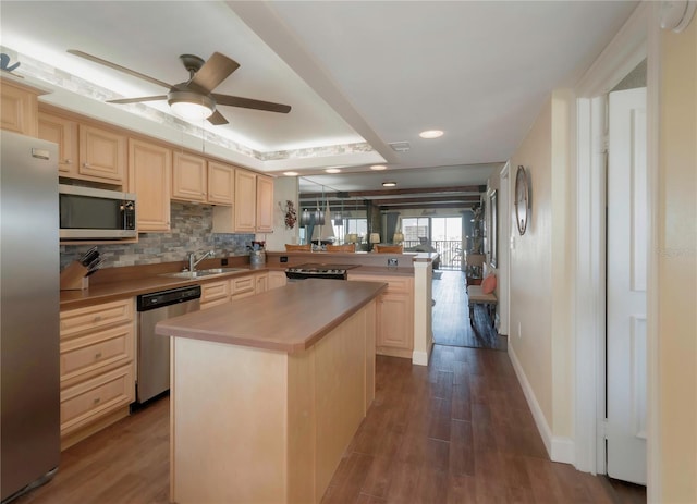 kitchen with dark wood-type flooring, light brown cabinetry, a sink, stainless steel appliances, and a peninsula