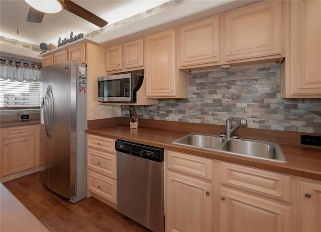 kitchen featuring tasteful backsplash, ceiling fan, appliances with stainless steel finishes, wood finished floors, and a sink