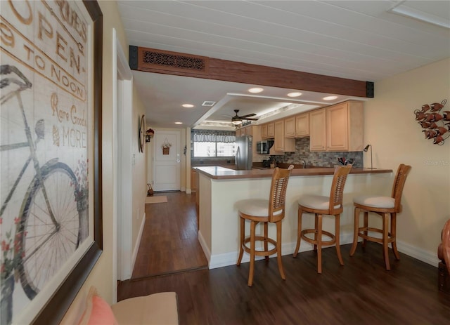 kitchen with dark wood-style floors, visible vents, a peninsula, stainless steel appliances, and decorative backsplash