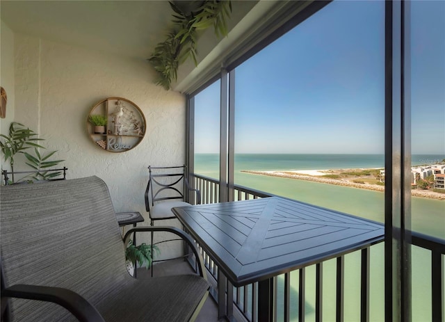 balcony with a water view and a view of the beach