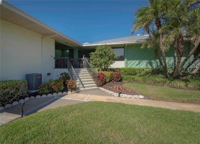 doorway to property featuring central air condition unit, stucco siding, and a yard