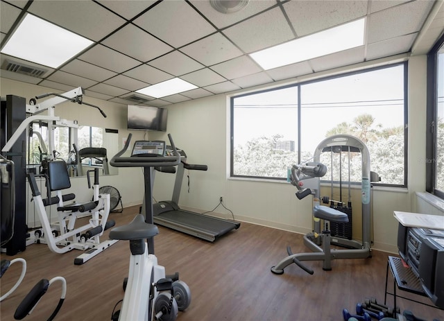 gym with wood finished floors, visible vents, a drop ceiling, and baseboards