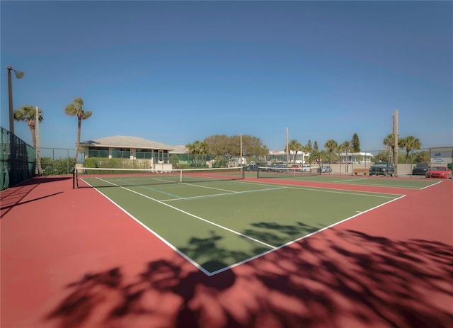 view of tennis court with community basketball court and fence