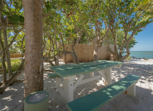 view of swimming pool with a patio, fence, a view of the beach, and a water view