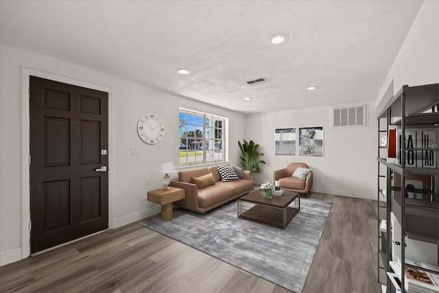 living area with visible vents, recessed lighting, baseboards, and wood finished floors