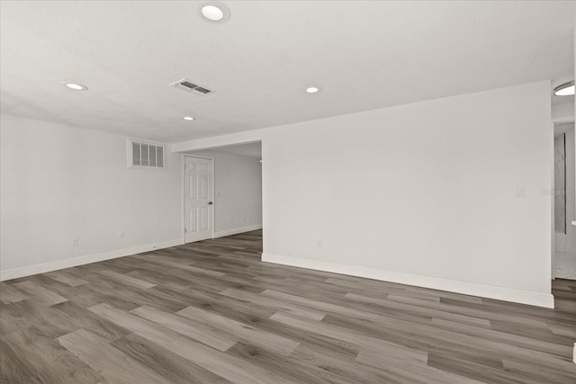 empty room featuring visible vents, recessed lighting, baseboards, and wood finished floors