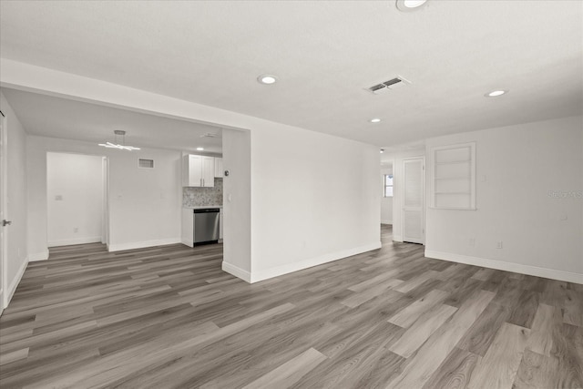 unfurnished living room with visible vents, baseboards, and wood finished floors