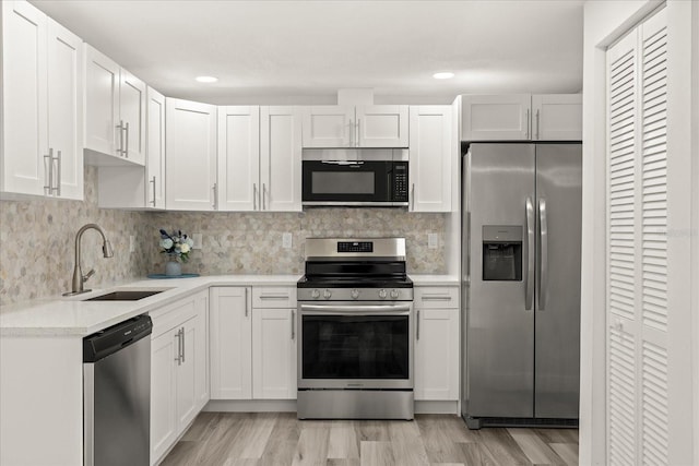 kitchen featuring decorative backsplash, light wood-style flooring, appliances with stainless steel finishes, white cabinetry, and a sink