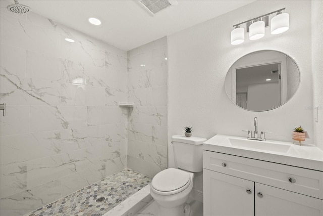 full bath with vanity, toilet, visible vents, and a tile shower