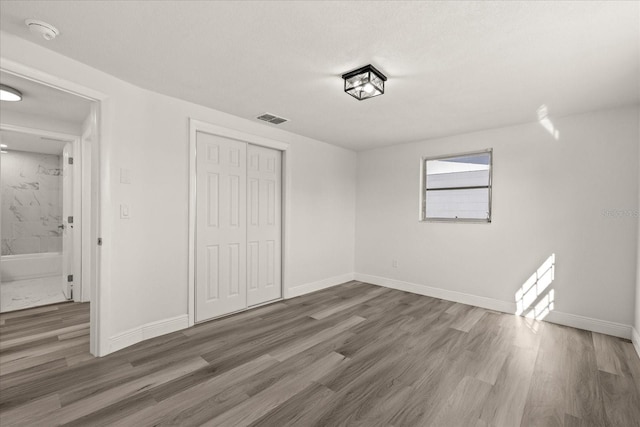 unfurnished bedroom featuring visible vents, baseboards, and wood finished floors