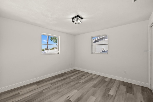 empty room featuring wood finished floors, baseboards, and a textured ceiling