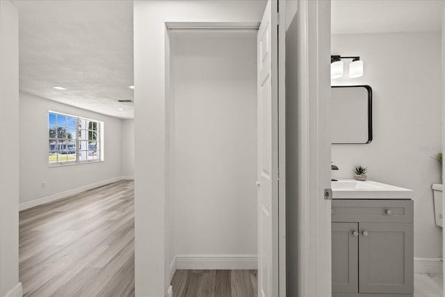 bathroom featuring vanity, wood finished floors, and baseboards