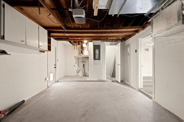 garage with electric panel, concrete block wall, and a garage door opener