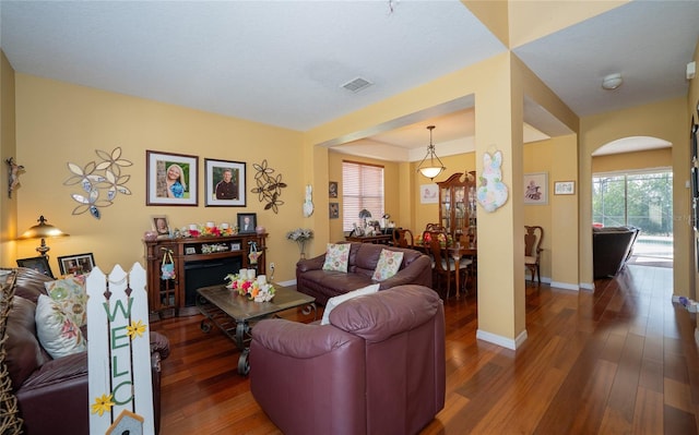 living area featuring arched walkways, visible vents, baseboards, and wood finished floors