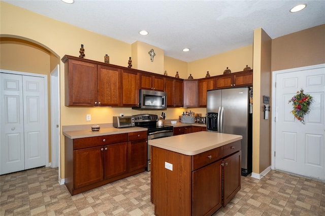 kitchen with a kitchen island, light countertops, recessed lighting, appliances with stainless steel finishes, and arched walkways