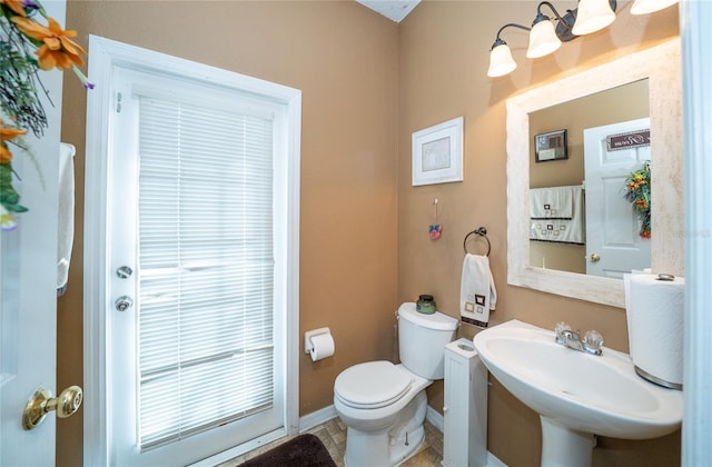 bathroom featuring toilet, baseboards, and a sink