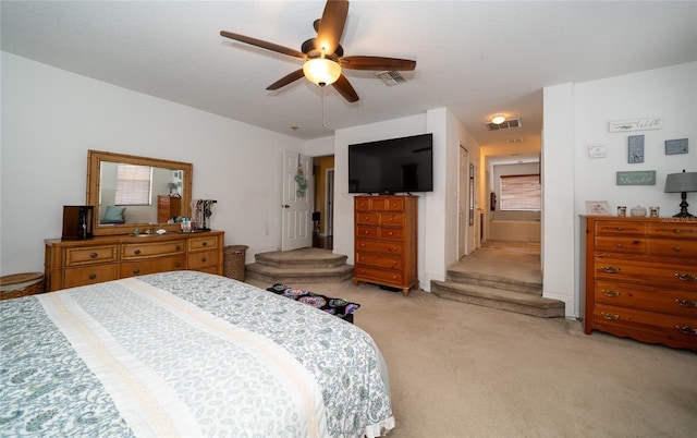 bedroom featuring a ceiling fan, visible vents, and light carpet