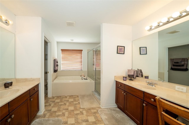 bathroom with visible vents, two vanities, a sink, a shower stall, and a garden tub