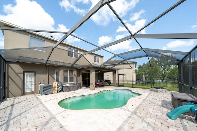 view of pool with glass enclosure, a fenced in pool, fence, a hot tub, and a patio area