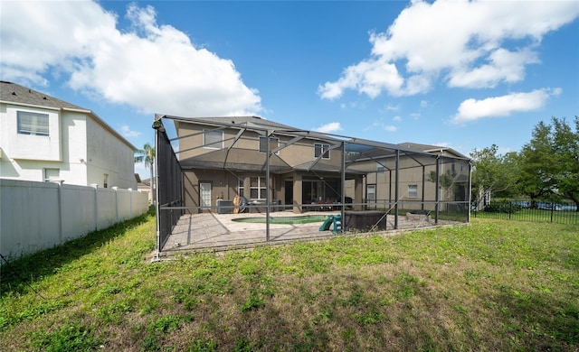 rear view of house featuring a patio area, a yard, a fenced backyard, and a lanai