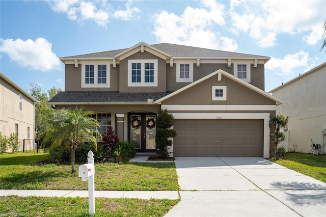 view of front facade with a front yard, french doors, driveway, and stucco siding