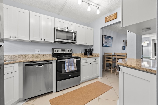 1986 Pelican Landing Blvd Unit 1514, Clearwater, FL 33762 - kitchen featuring light tile patterned floors, light stone countertops, white cabinets, appliances with stainless steel finishes, and a textured ceiling