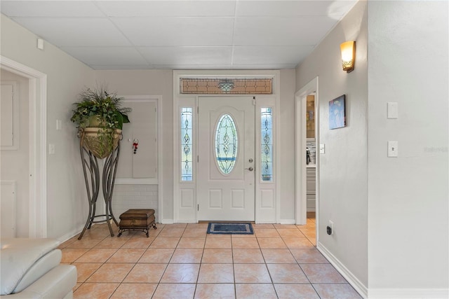 entrance foyer with light tile patterned flooring, baseboards, and a drop ceiling