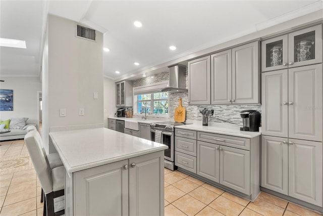 kitchen with visible vents, gray cabinets, stainless steel appliances, crown molding, and wall chimney range hood