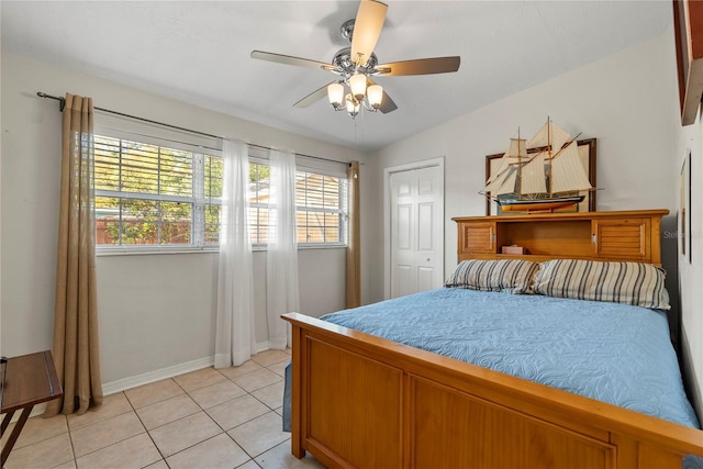 bedroom featuring light tile patterned floors, baseboards, a ceiling fan, and a closet