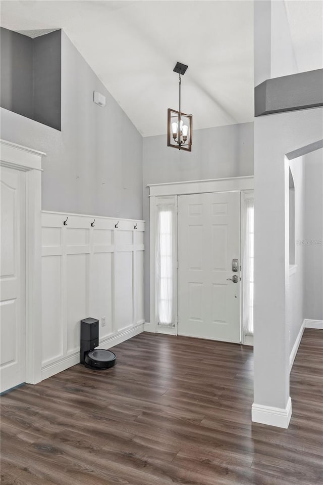 entryway featuring vaulted ceiling, a chandelier, dark wood-style flooring, and a decorative wall