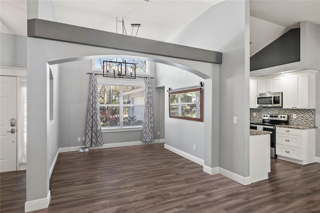 interior space with baseboards, arched walkways, a notable chandelier, and dark wood-style flooring