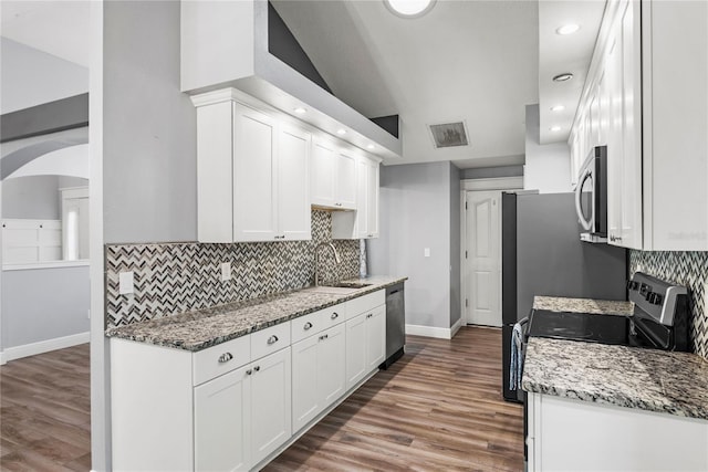 kitchen with light stone counters, wood finished floors, appliances with stainless steel finishes, and white cabinets