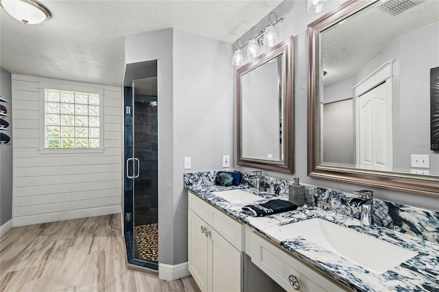 full bath featuring visible vents, a stall shower, a textured ceiling, and a sink