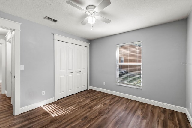 unfurnished bedroom featuring visible vents, baseboards, a closet, a textured ceiling, and dark wood-style flooring