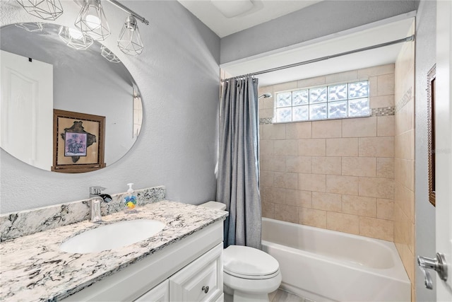 full bath with vanity, toilet, shower / tub combo with curtain, and a textured wall