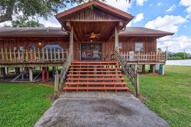 6501 62nd St N, Pinellas Park, FL 33781 - view of exterior entry featuring board and batten siding, ceiling fan, a deck, and a yard