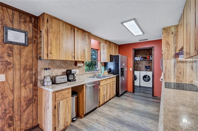 6501 62nd St N, Pinellas Park, FL 33781 - kitchen with light countertops, stainless steel appliances, a sink, light wood-style floors, and washing machine and dryer