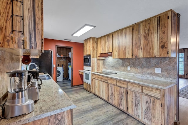 6501 62nd St N, Pinellas Park, FL 33781 - kitchen with light countertops, oven, washer / clothes dryer, stainless steel microwave, and under cabinet range hood