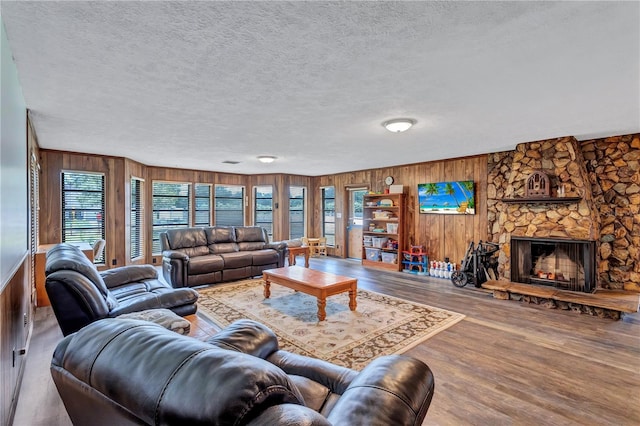 6501 62nd St N, Pinellas Park, FL 33781 - living room featuring a textured ceiling, wood finished floors, wooden walls, and a stone fireplace