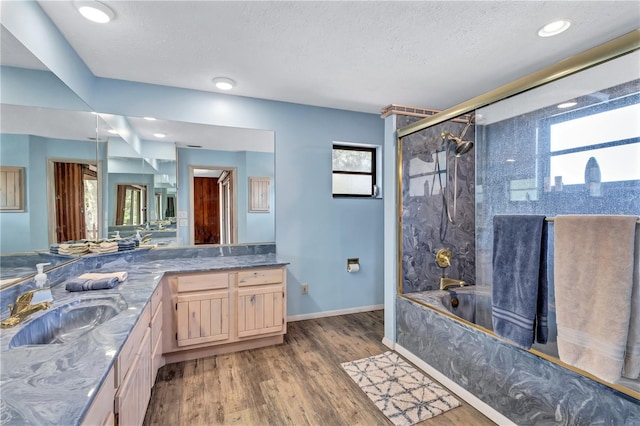 6501 62nd St N, Pinellas Park, FL 33781 - bathroom featuring vanity, wood finished floors, a textured ceiling, baseboards, and shower / bath combination with glass door