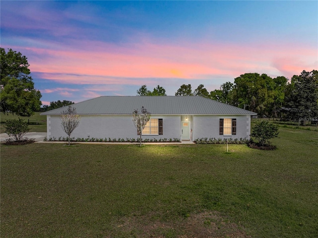 ranch-style home featuring a yard and metal roof