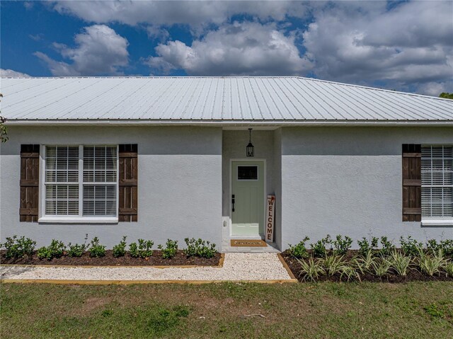view of front of home featuring stucco siding and metal roof