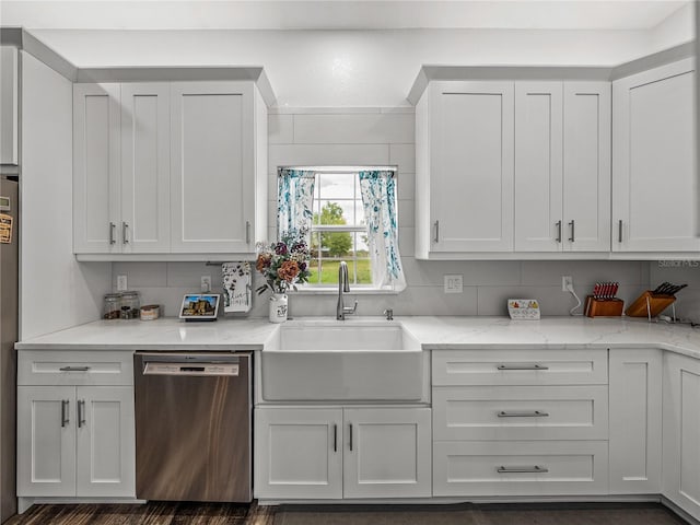 kitchen featuring stainless steel dishwasher, white cabinets, light stone countertops, and a sink