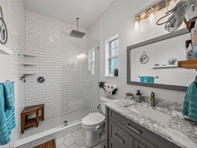 bathroom with vanity, tile patterned floors, toilet, and a tile shower