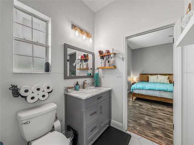 bathroom featuring vanity, ensuite bath, toilet, and baseboards